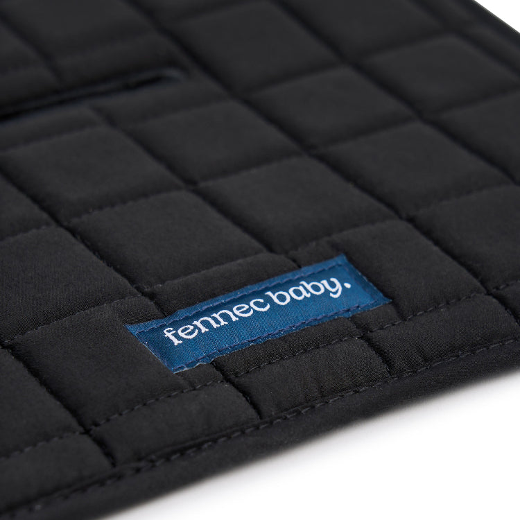 A close-up of a black quilted baby pram liner with a blue fabric brand label reading 'fennec baby.' on a white background.