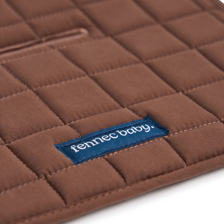 A close-up of a brown quilted baby pram liner with a blue fabric brand label reading 'fennec baby.' on a white background.